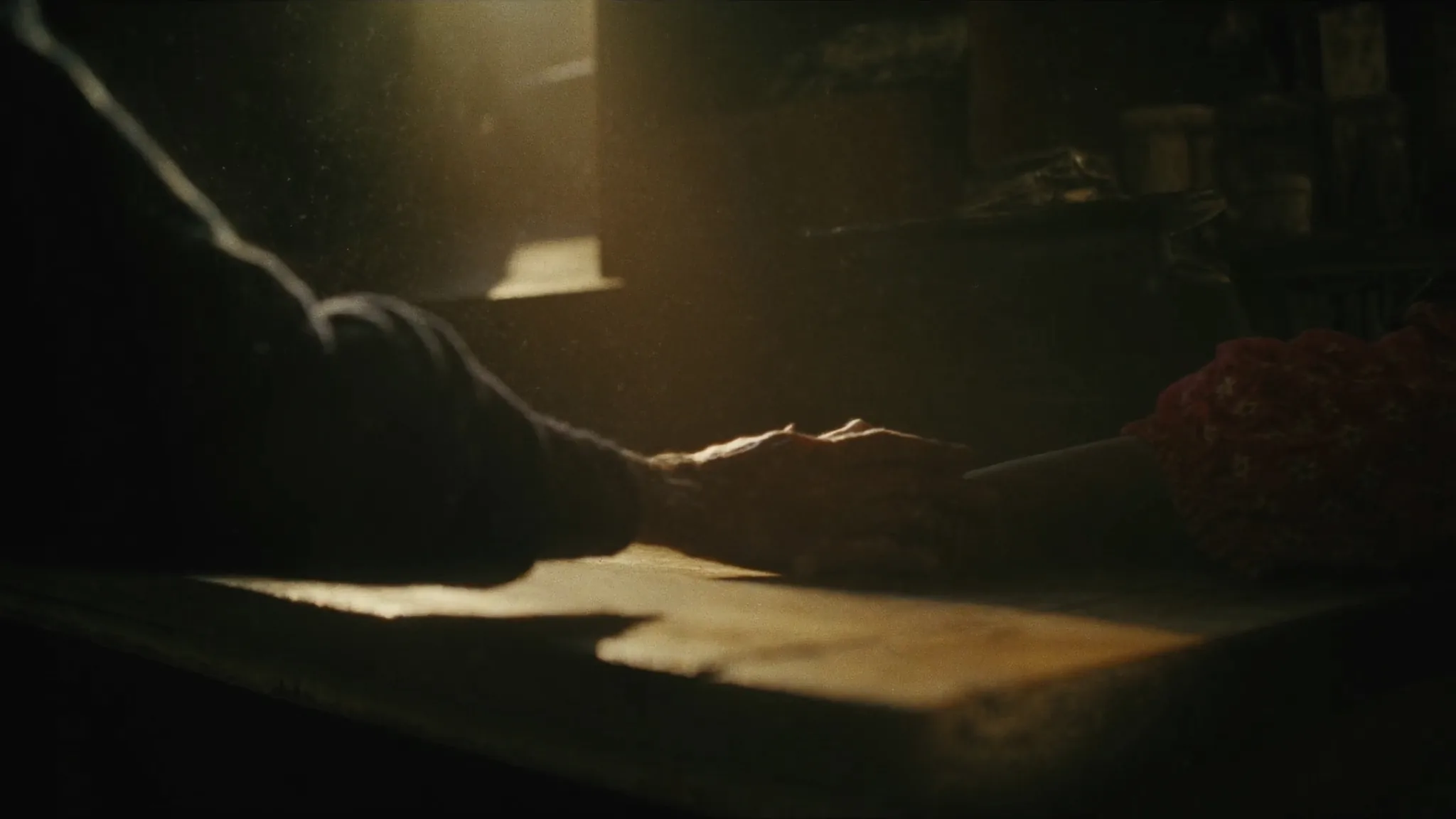 มือของผู้สูงอายุและมือของเด็กเอื้อมเข้าหากันบนโต๊ะไม้ ในแสงอุ่นจากหน้าต่าง